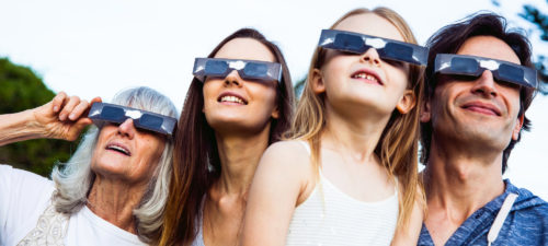 Family watching solar eclipse with safety glasses on.